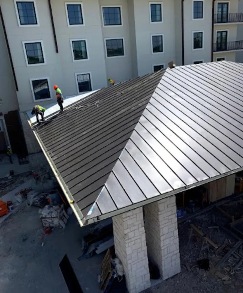 Crew installing standing seam metal roof panels on a commercial project in Auburn Hills